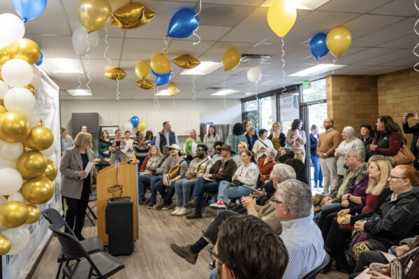 guests at New Narrative East listen to Julie Ibrahim, CEO, speak at a podium
