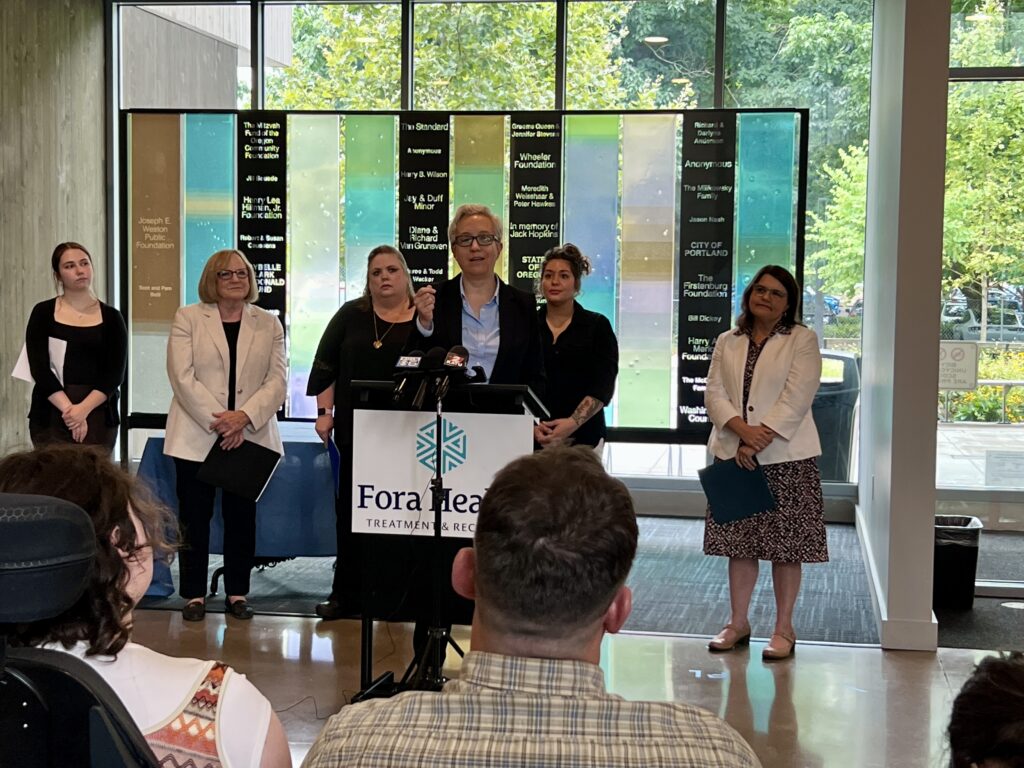 Governor Kotek addresses the guests at the signing in initial remarks, surrounded by providers including CEO Julie Ibrahim