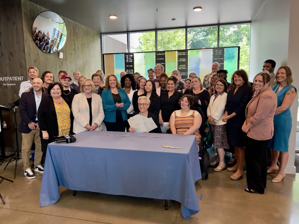 Governor Kotek poses with providers and advocates holding the signed bills