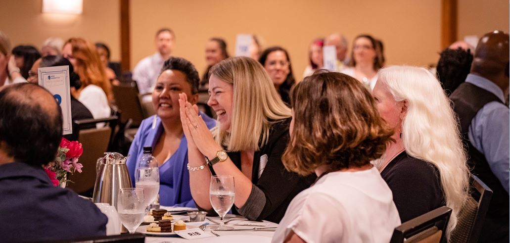 Gala attendees laughing at a table and clapping