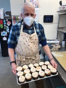 Matt S. in an apron holding a tray of baked goods