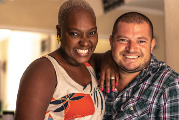 two people-a Black woman and multiethnic man face the camera smiling