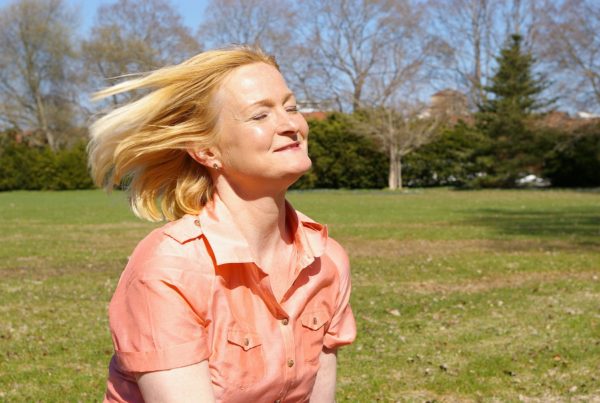 Blonde woman smiling with eyes closed into the sun